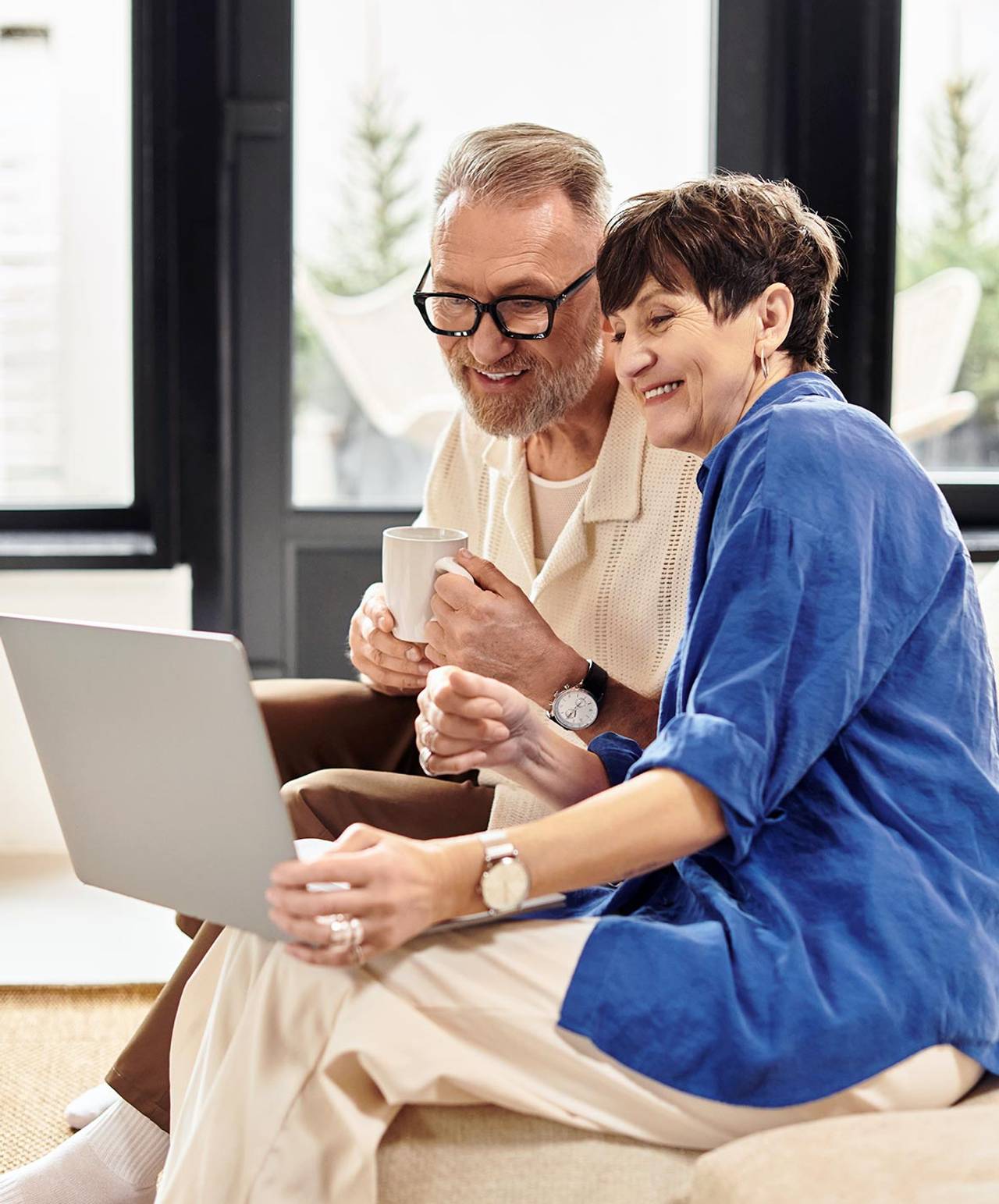 A senior couple reading AMAC newsletters together on a laptop