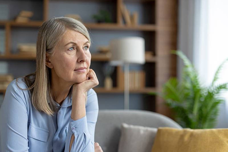 An older woman sitting alone at home, deep in thought