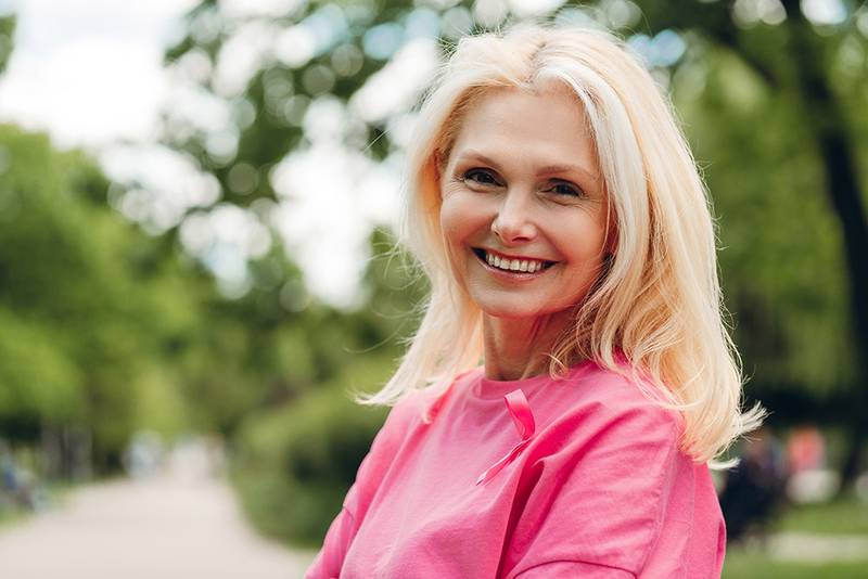 A smiling woman in her fifties outdoors in a park